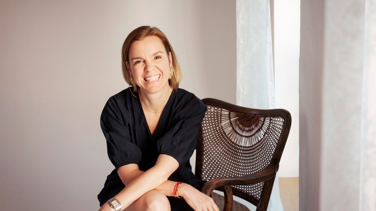 Smiling person sitting on a chair with crossed arms in a well-lit room.